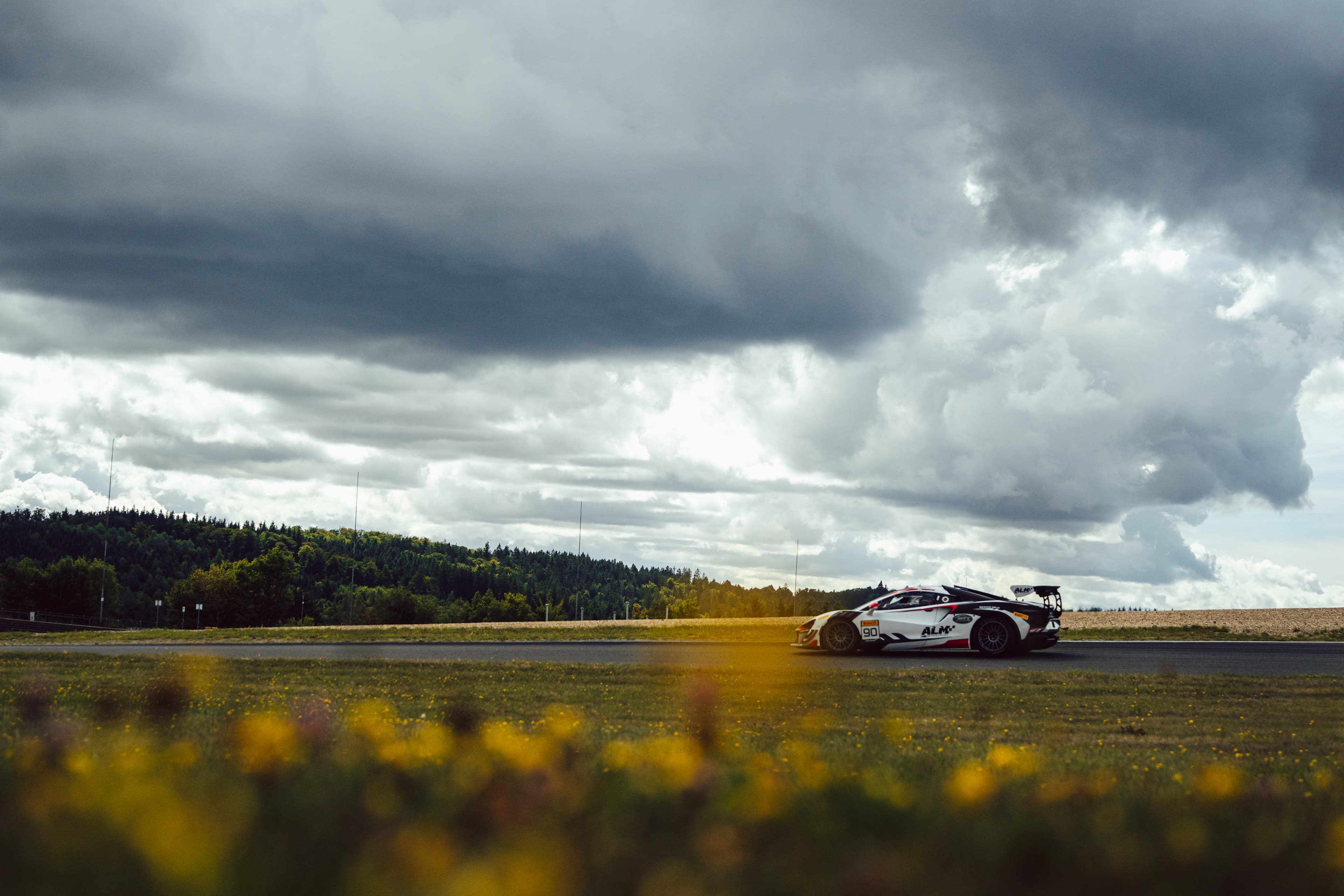 McLaren GT4 side-on under a stormy sky